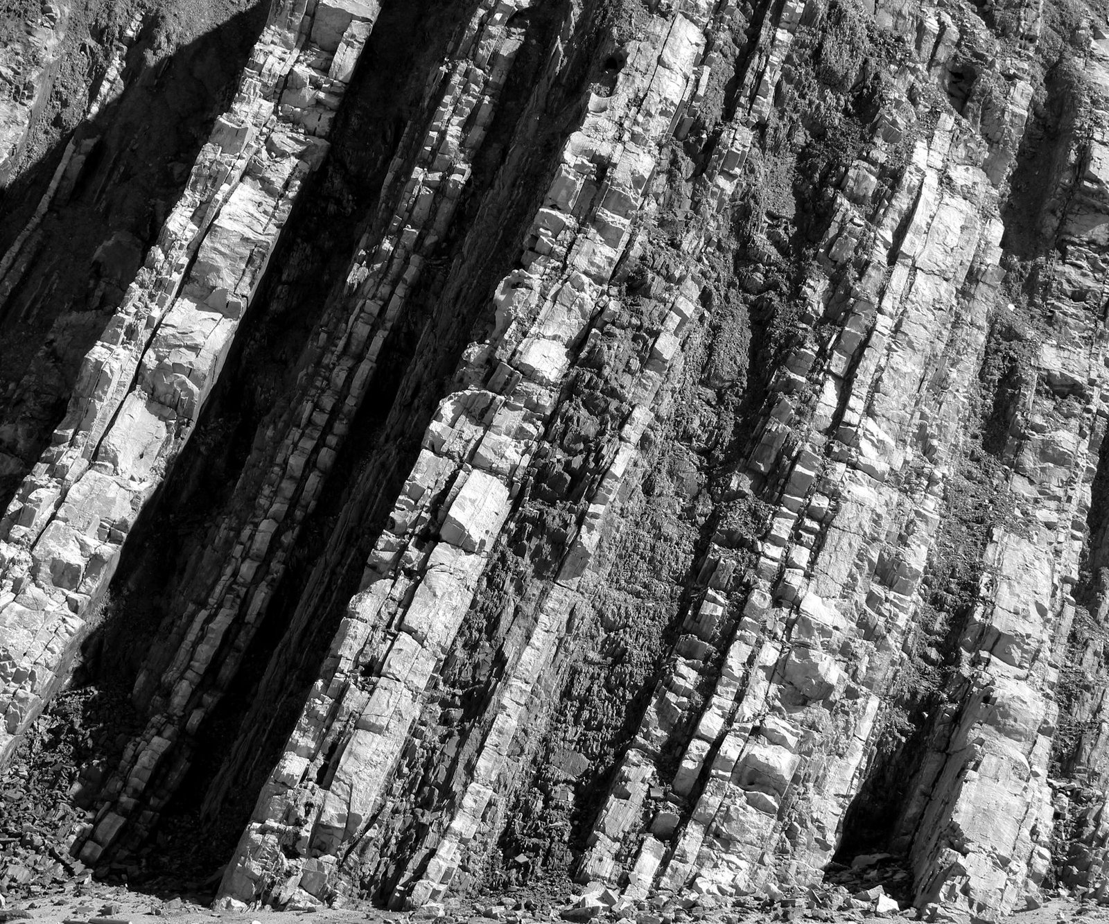 A cliff face of tilted rock layers, photographed in black and white